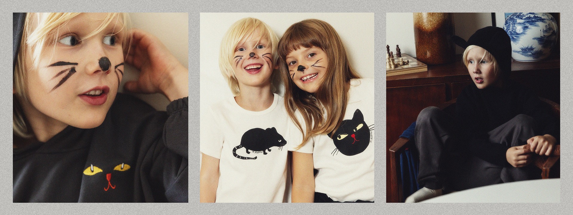 Two children lie on a wooden floor, smiling with whiskers painted on their faces, wearing T-shirts with cat designs.