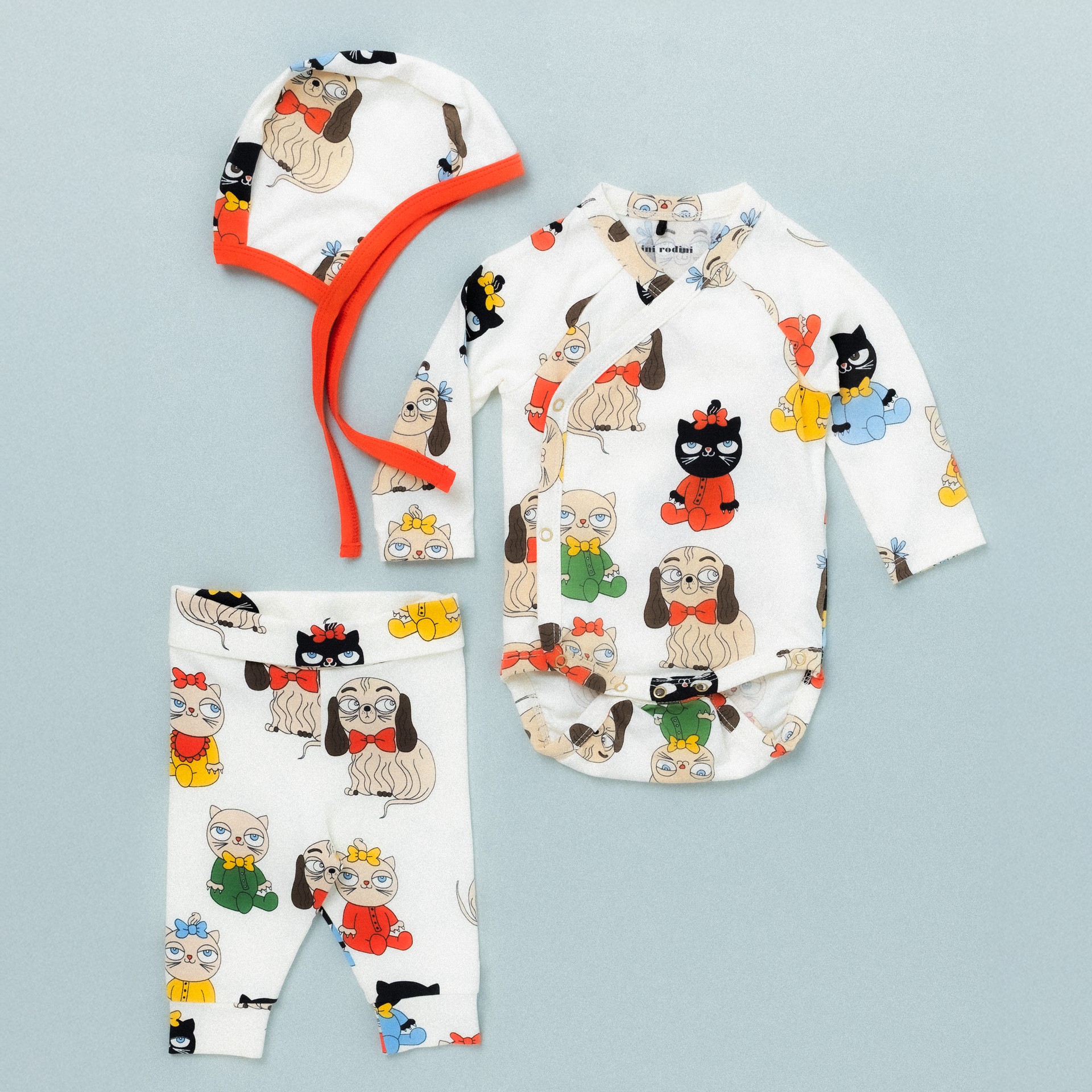 Infant clothing set with Minibabies print from Mini Rodini, featuring a hat, bodysuit, and leggings. White fabric with colorful Minibabies print.