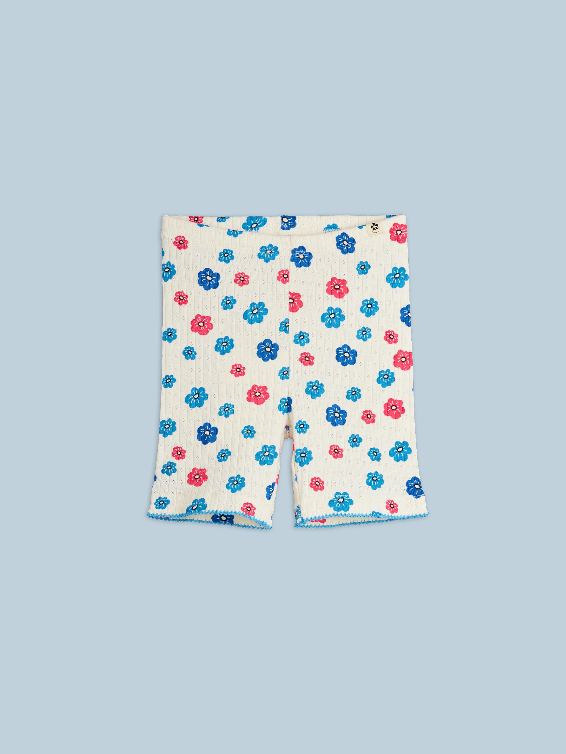 White shorts with blue and pink flower prints, set against a light blue background.