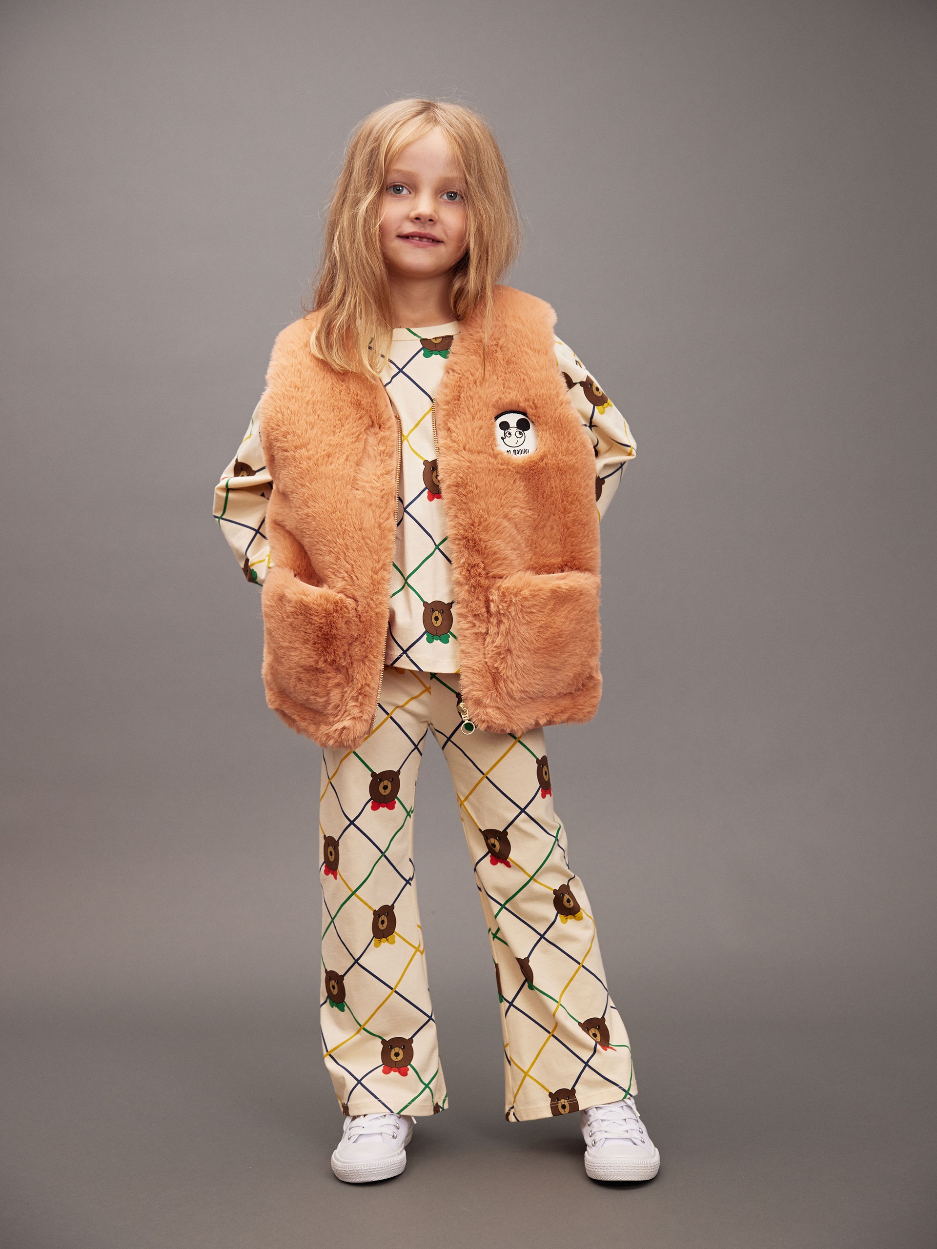Girl wearing Bear check flared trousers, Bear check long sleeve t-shirt and Ritzratz patch faux fur vest from Mini Rodini