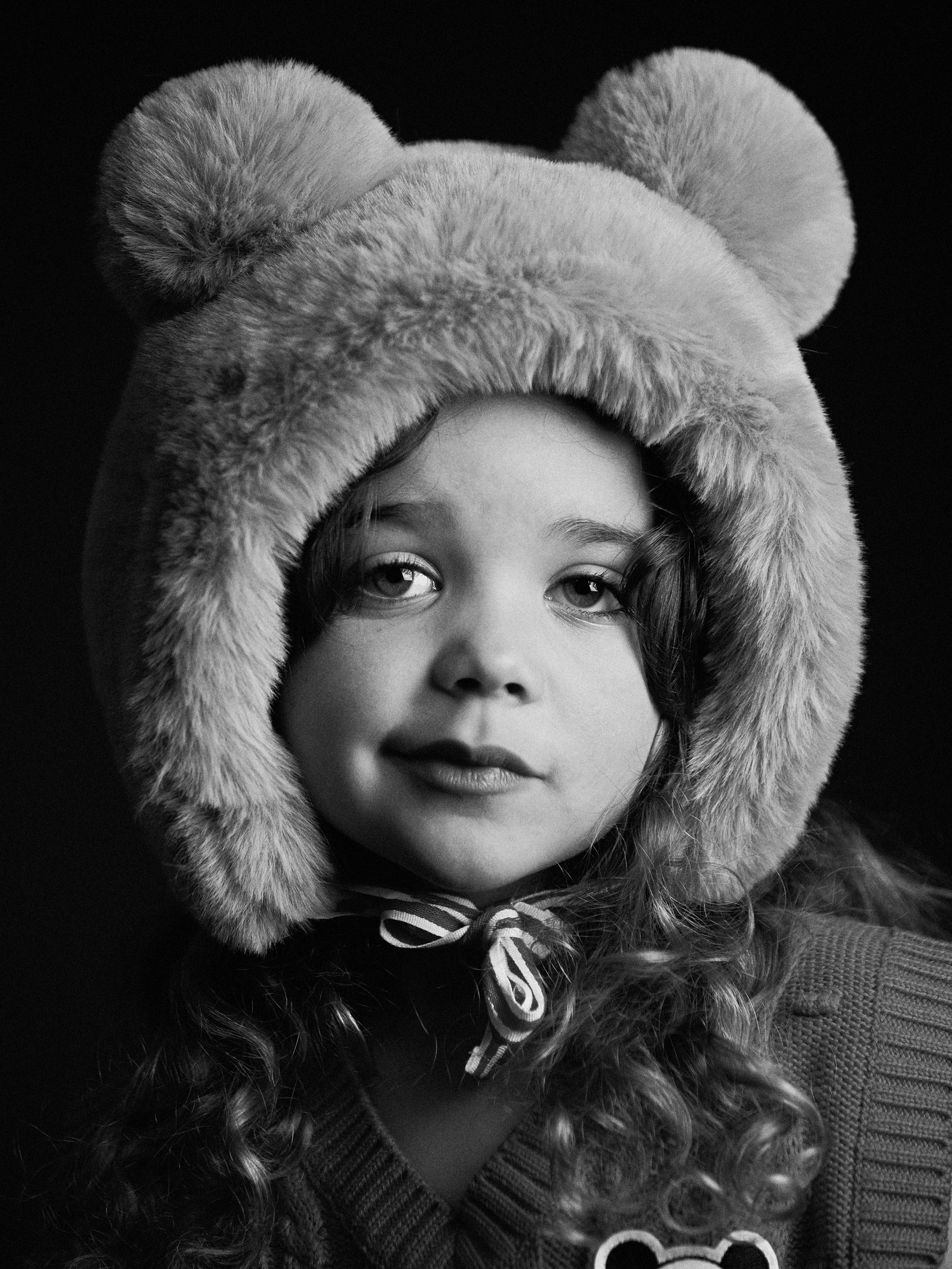 Black and white image of a girl wearing Faux fur ear hat from Mini Rodini
