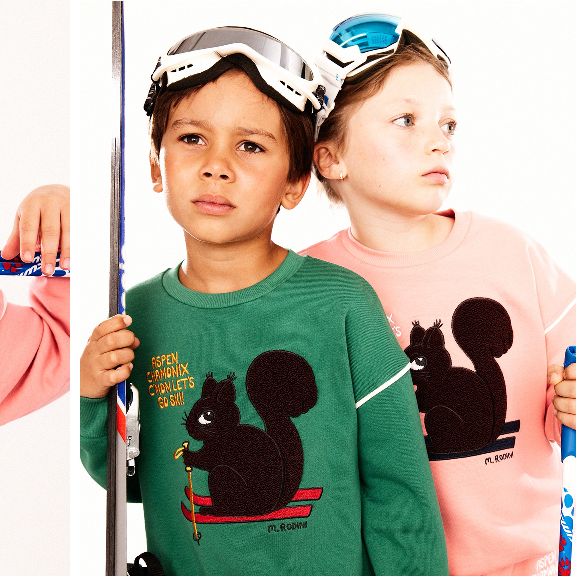 Two children dressed in playful t-shirts featuring a skiing squirrel design with text “Aspen Chamonix C’mon Let’s Go Ski!”