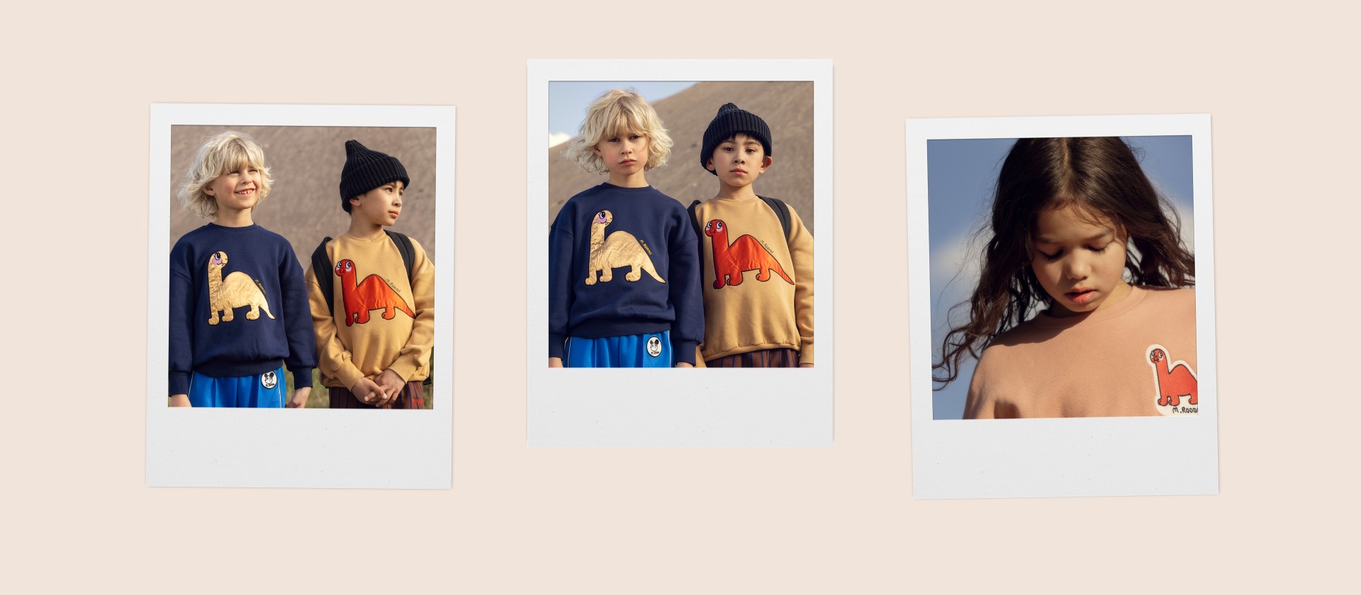 Two children wearing dinosaur sweaters; one in navy blue with a yellow dinosaur, the other in tan with a red dinosaur