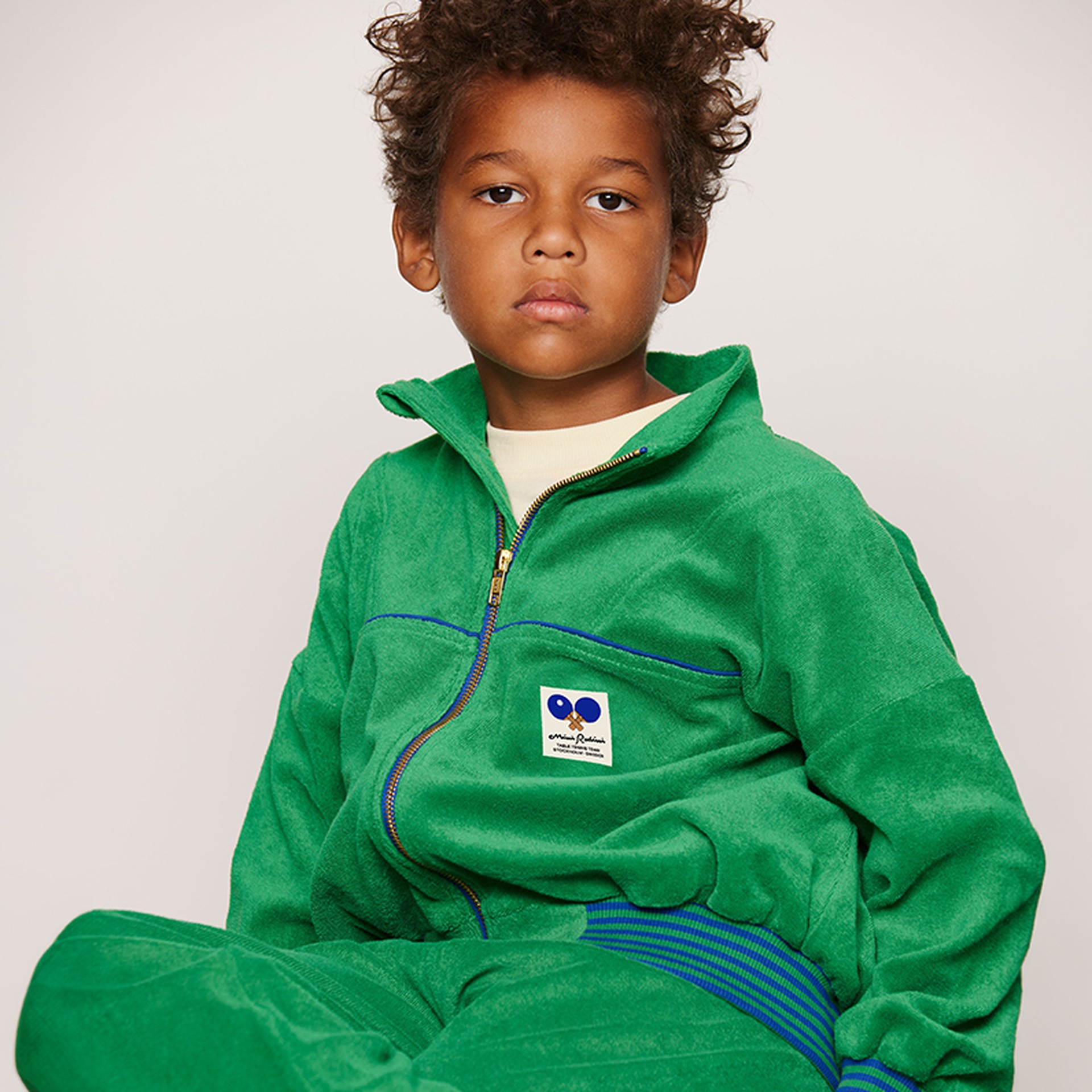 Child in a green Terry tracksuit from Mini Rodini Table Tennis collection