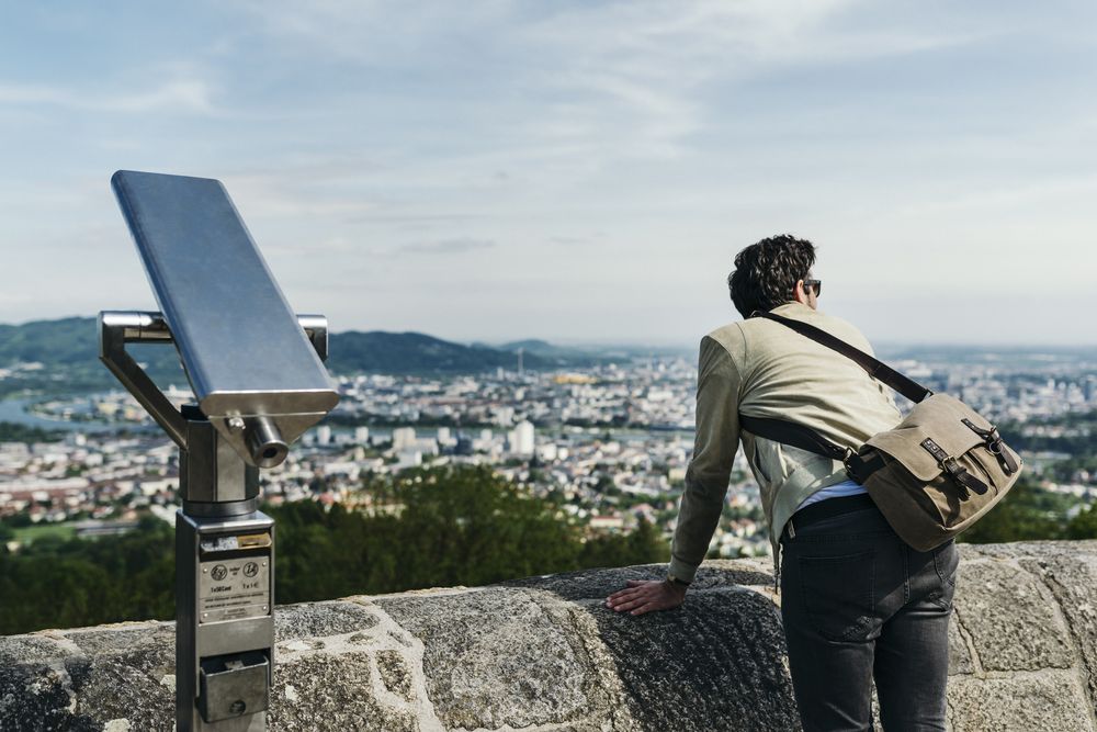 Ein Mann steht auf dem Pöstlingberg und blickt über die ganze Stadt Linz