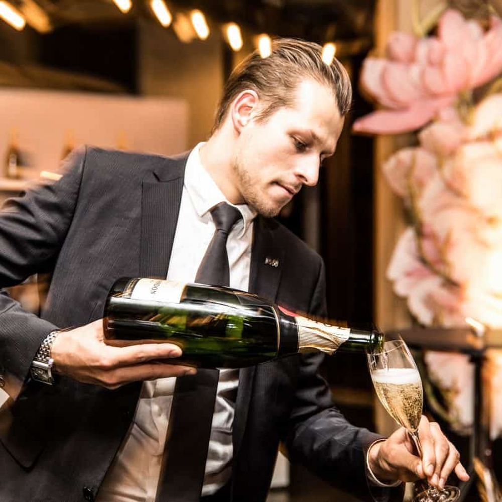 Mann der Champagner in ein Glas ausschenkt