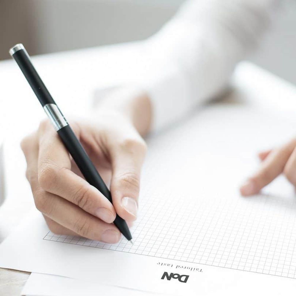 Jemand schreibt mit einem Stift auf ein Stück Papier