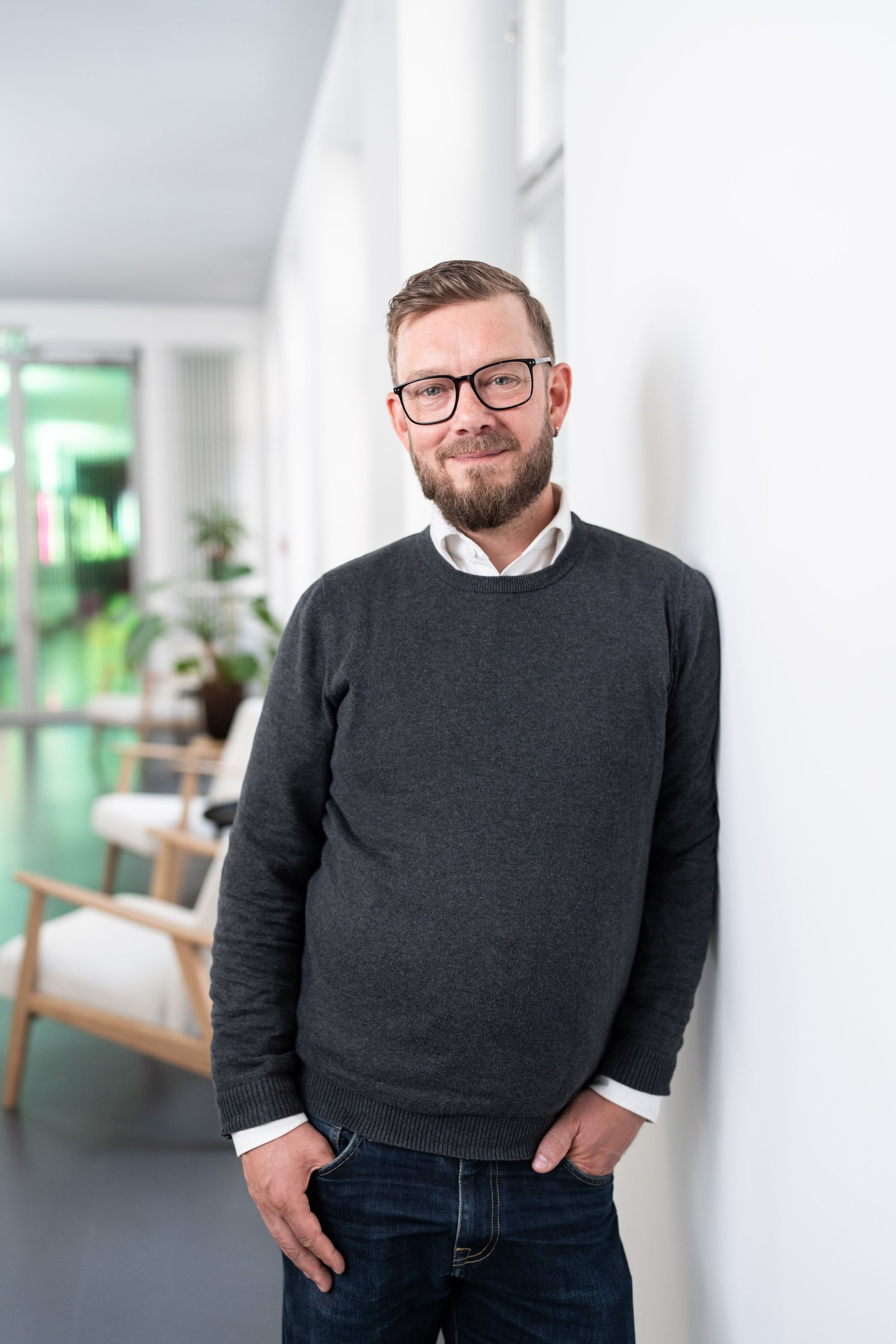 Chief Technology Officer Tim Straeter während er im Münchner Office an einer Wand lehnt.