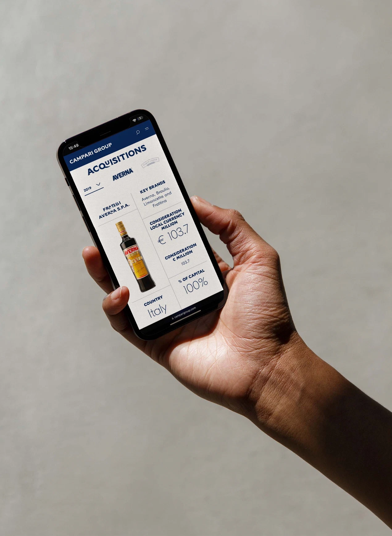 Hand holding a smartphone displaying Campari Group's acquisition info for Averna, highlighting purchase details and financial figures.