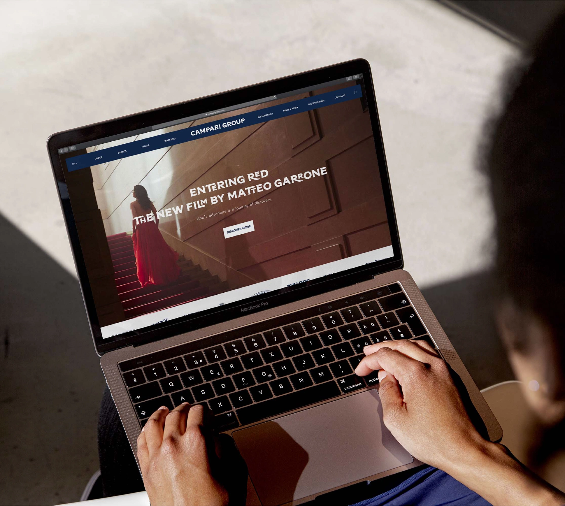 Person using a laptop displaying a website about "Entering Red," a film by Matteo Garrone, featuring a woman in a red dress on stairs.