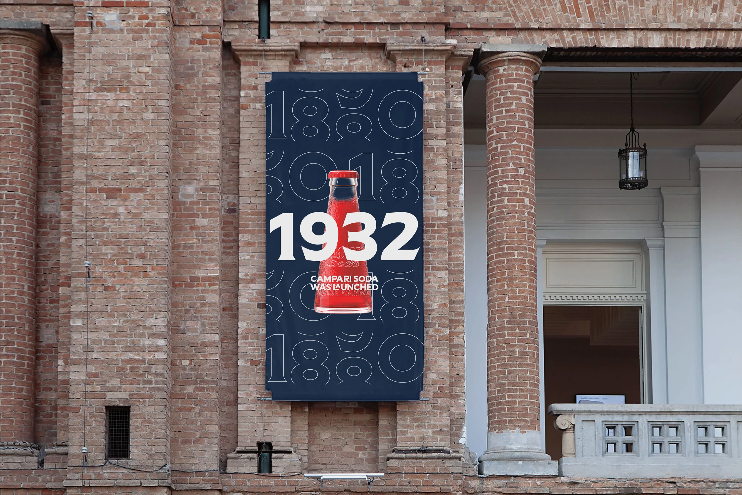 Sign on a brick wall showing a Campari soda bottle with "1932 Campari Soda was launched" text against a dark background.