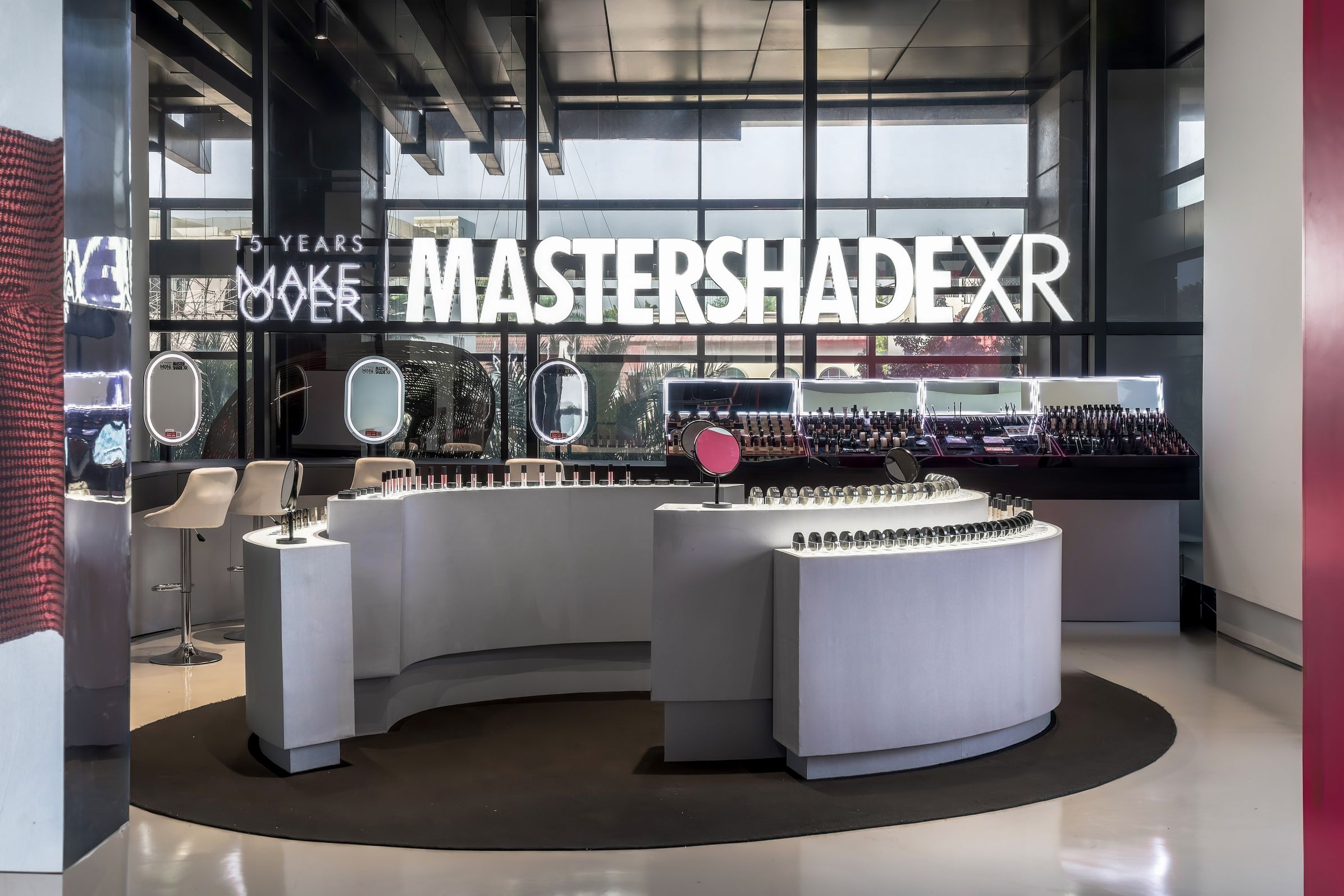 Modern cosmetics store interior with sleek white counters, round mirrors, and a "MASTERSHADE XR" sign on the wall. Makeover Mastershade event at Ashta Jakarta July 2025