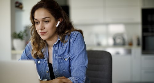 Woman sitting at a laptop with air pods in her ears
