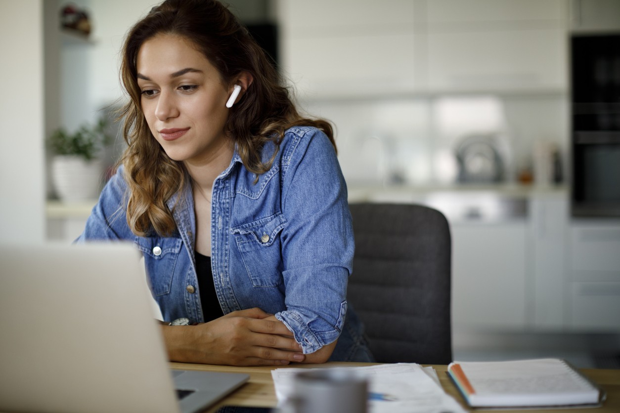 Woman sitting at a laptop with air pods in her ears