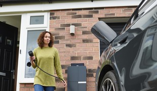 A person plugging in an vehicle for charging on a drive