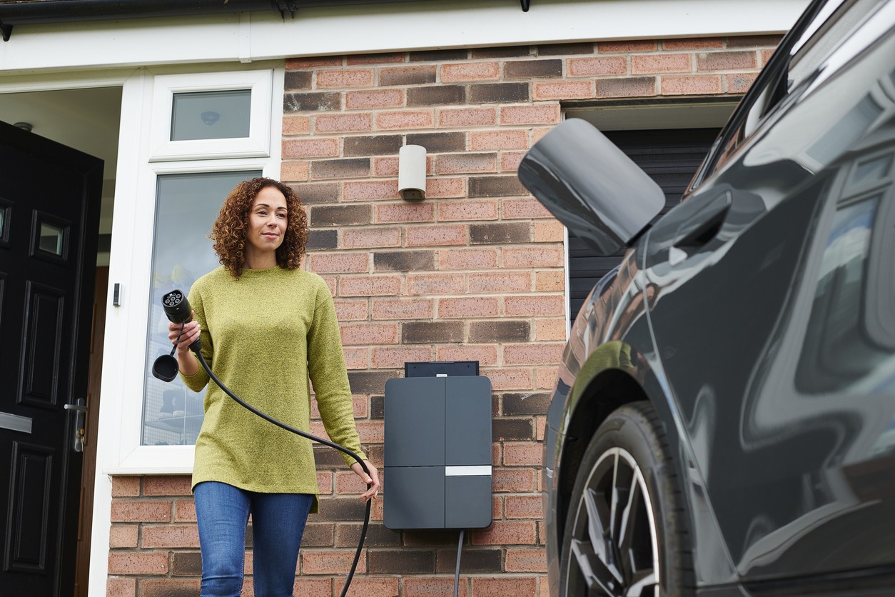 A person plugging in an vehicle for charging on a drive