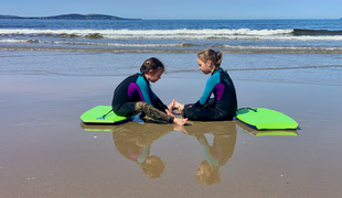 Two children sitting on a beach in Tasmania