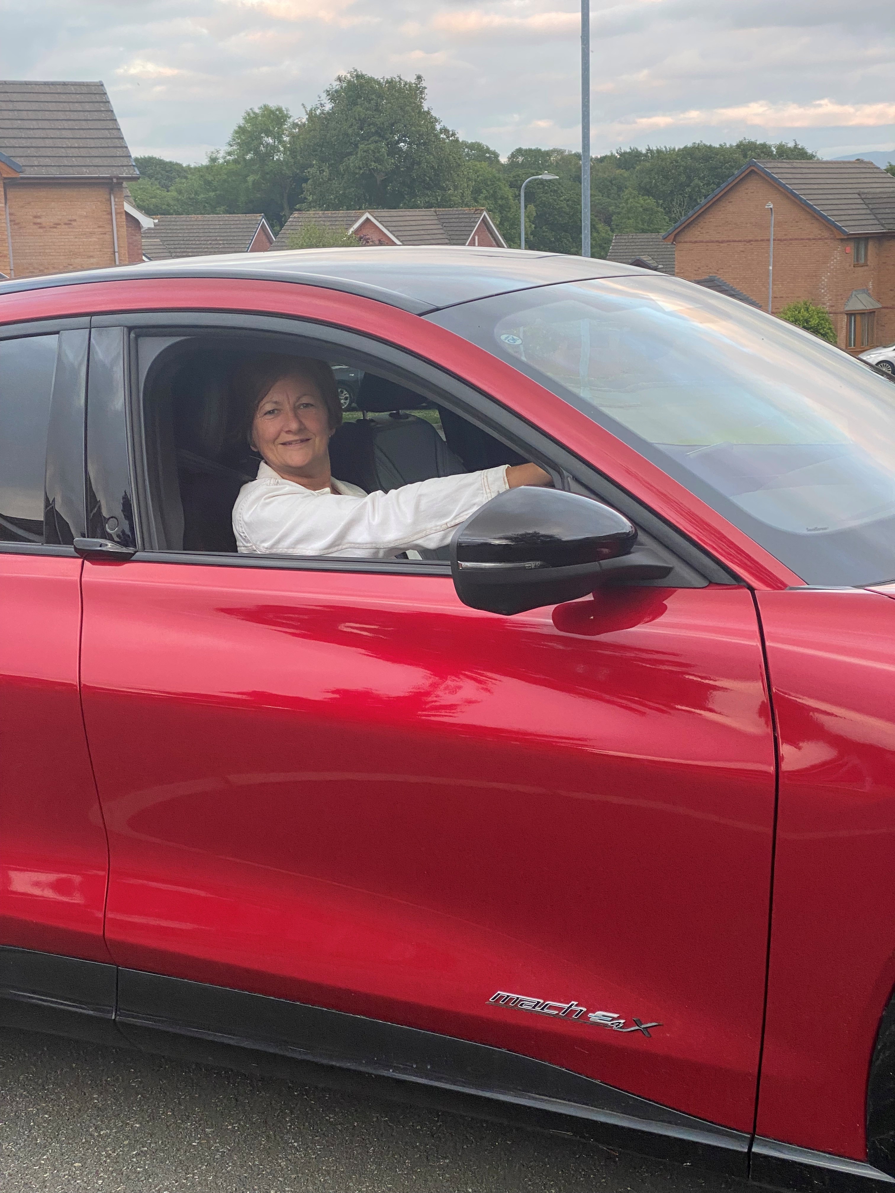 Gwenllian sitting in the driver seat of her red electric vehicle