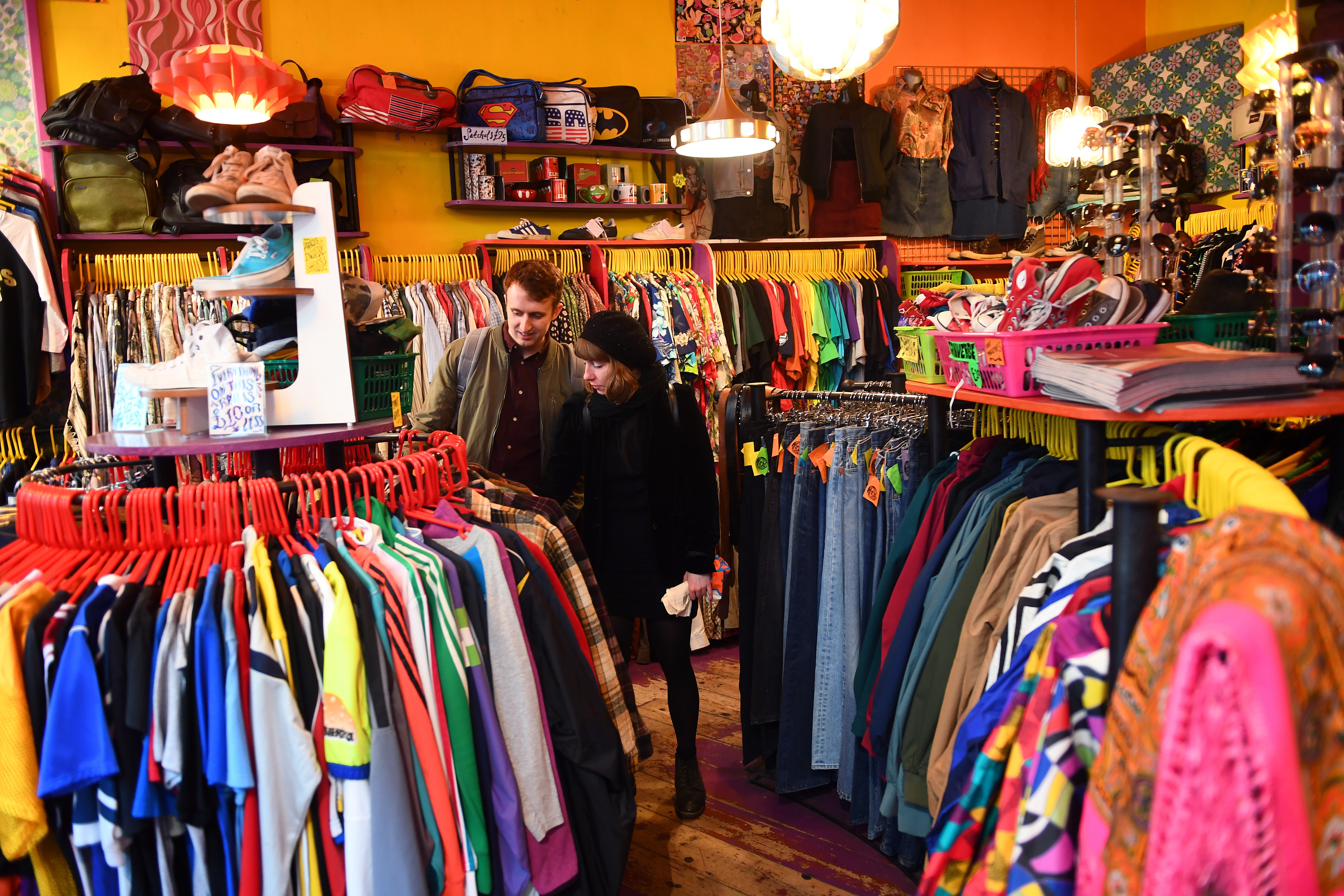 A man and woman in a second-hand vintage store looking through clothing rails