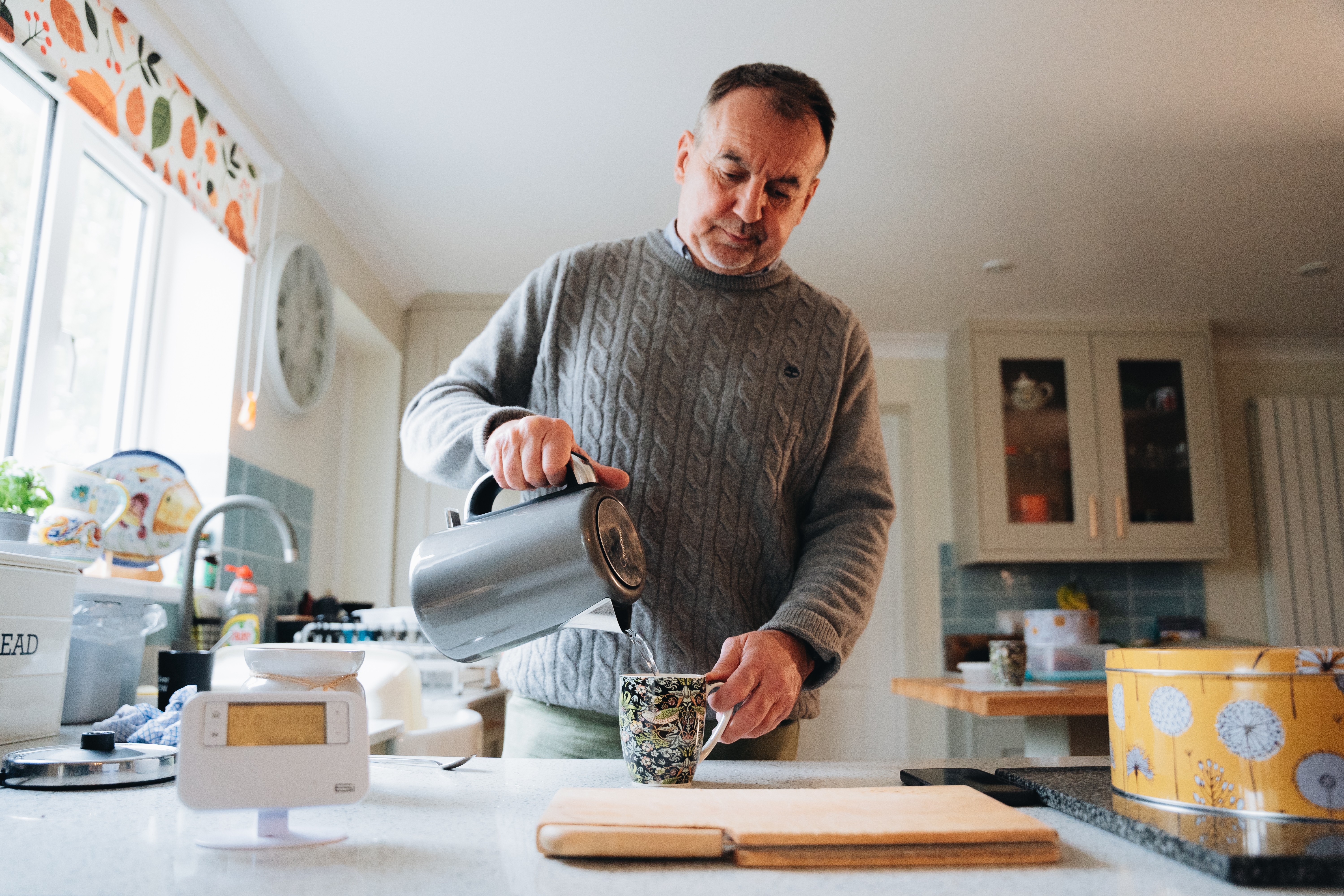 A man pouring water from a kettle into a cup of tea