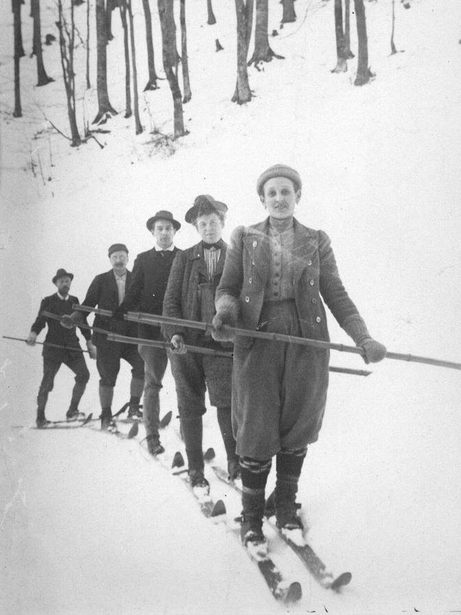 Mizzi-Langer-Kauba und Männer beim Skifahren.