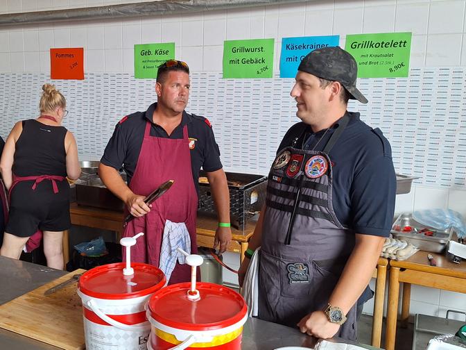 Zwei Feuerwehrmänner an der Grillstation beim Florianifest in Hainburg.