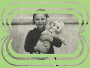 Ein altes Foto eines Mädchens mit einer Puppe, eingerahmt von grünen Elementen.