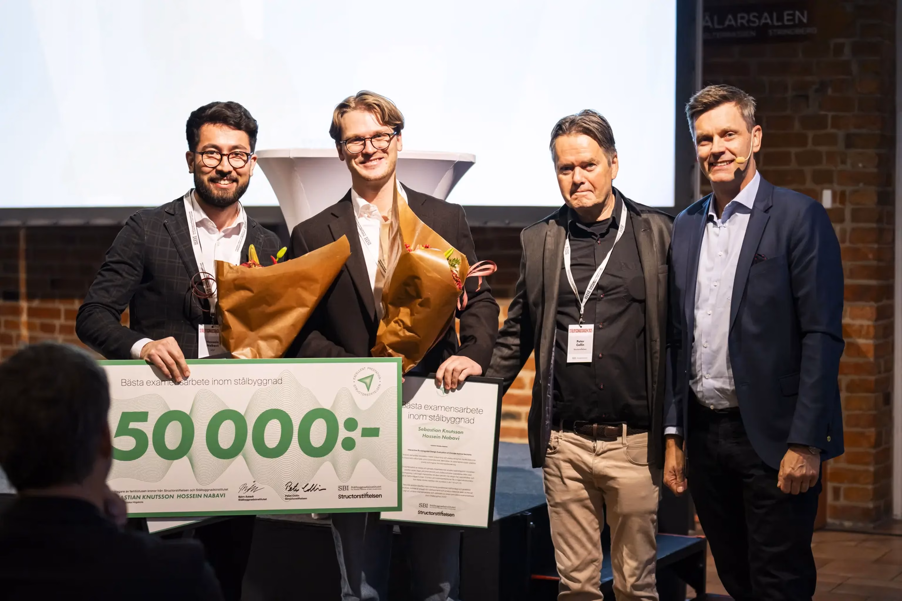 Fyra män står på en scen varav två av dessa håller i blommor och en stor check på 50 000 kr.