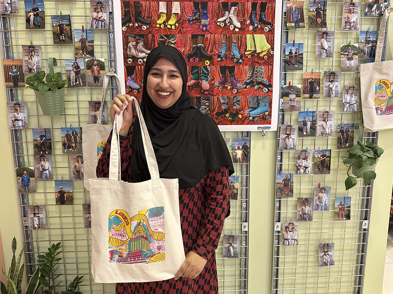 Young person in a hijjab holding the tote bag they've designed