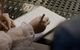 A person writing in a notebook in front of a mixing board.