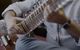 A man playing a sitar on the floor.
