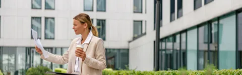 stylish-woman-analyst-working-with-documents-while-sitting-outside-modern-building-background