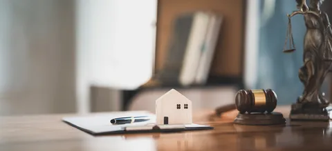 Documento legal e casa em miniatura representando a reforma fiscal da habitação em Portugal