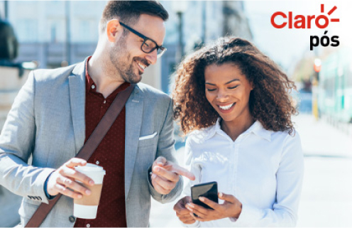 Um homem e uma mulher sorrindo olhando o celular. Ela segura o smartphone e o homem um copo de café. A foto foi tirada ao ar livre e tem o logotipo do "Claro pós" no canto superior direito.