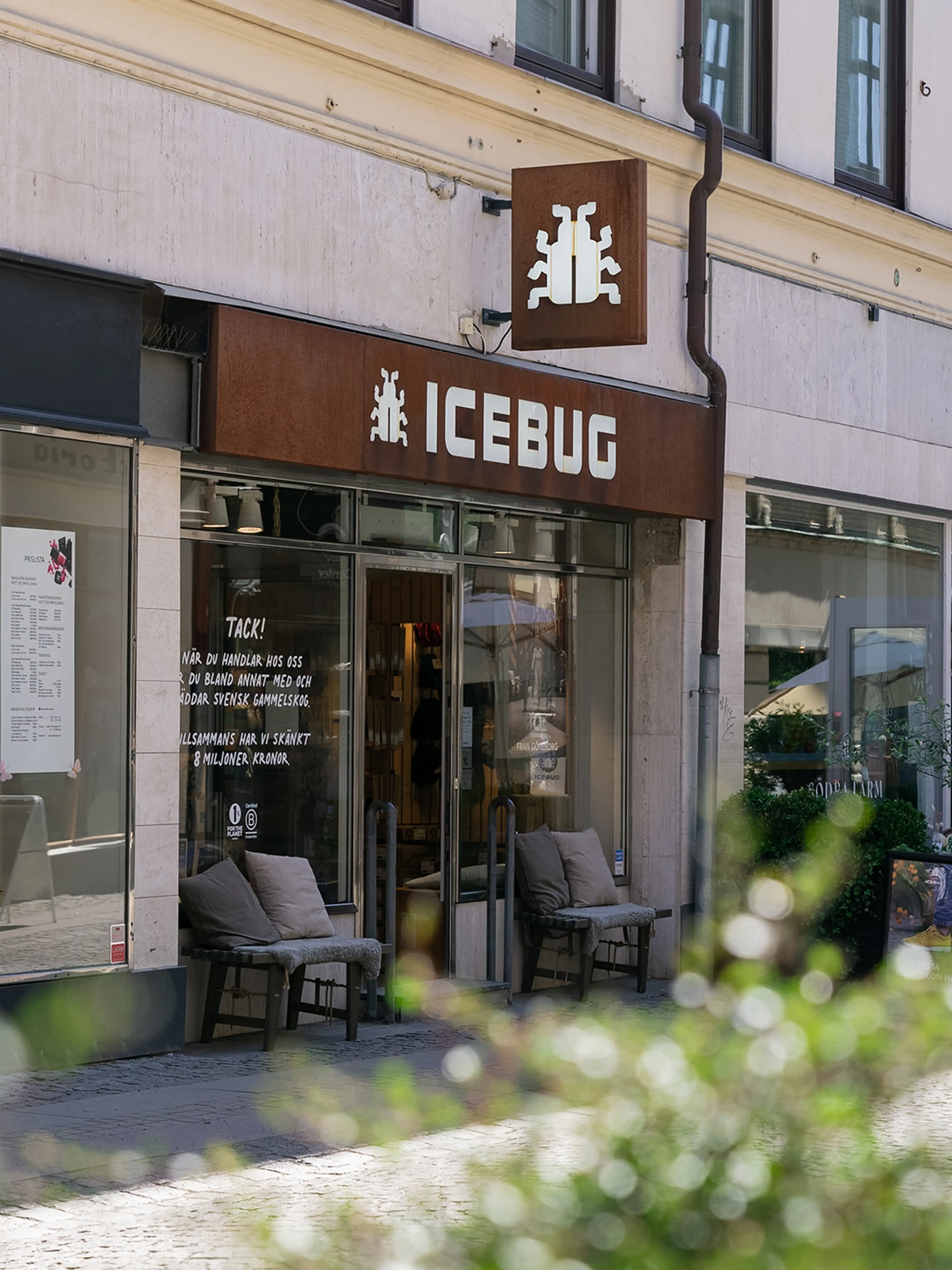Street view of a the Icebug store with a sign reading "ICEBUG." There are two chairs outside the entrance, and plants partially frame the scene.