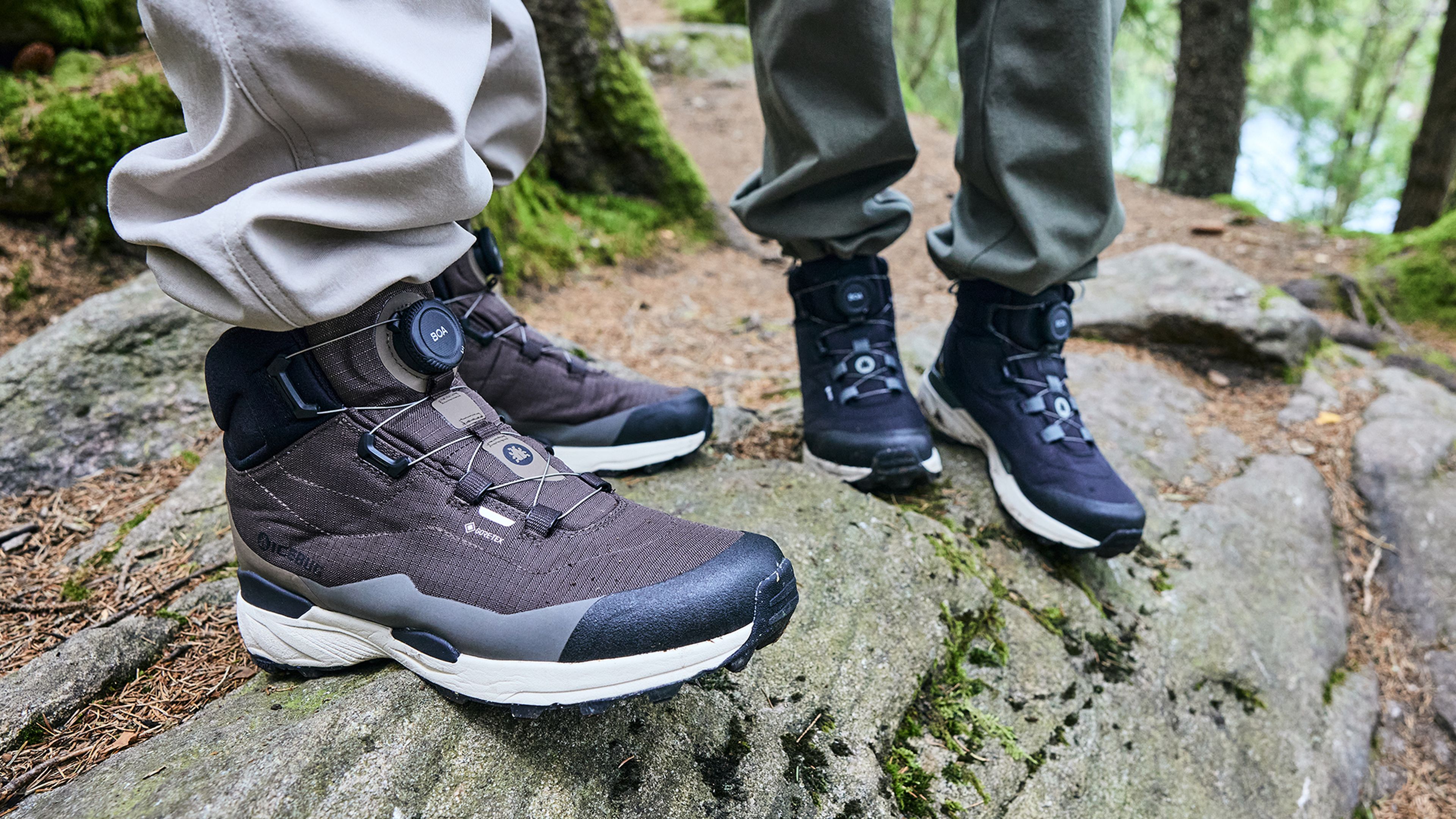 Two people hiking on a rocky forest path, wearing rugged hiking boots with adjustable laces.