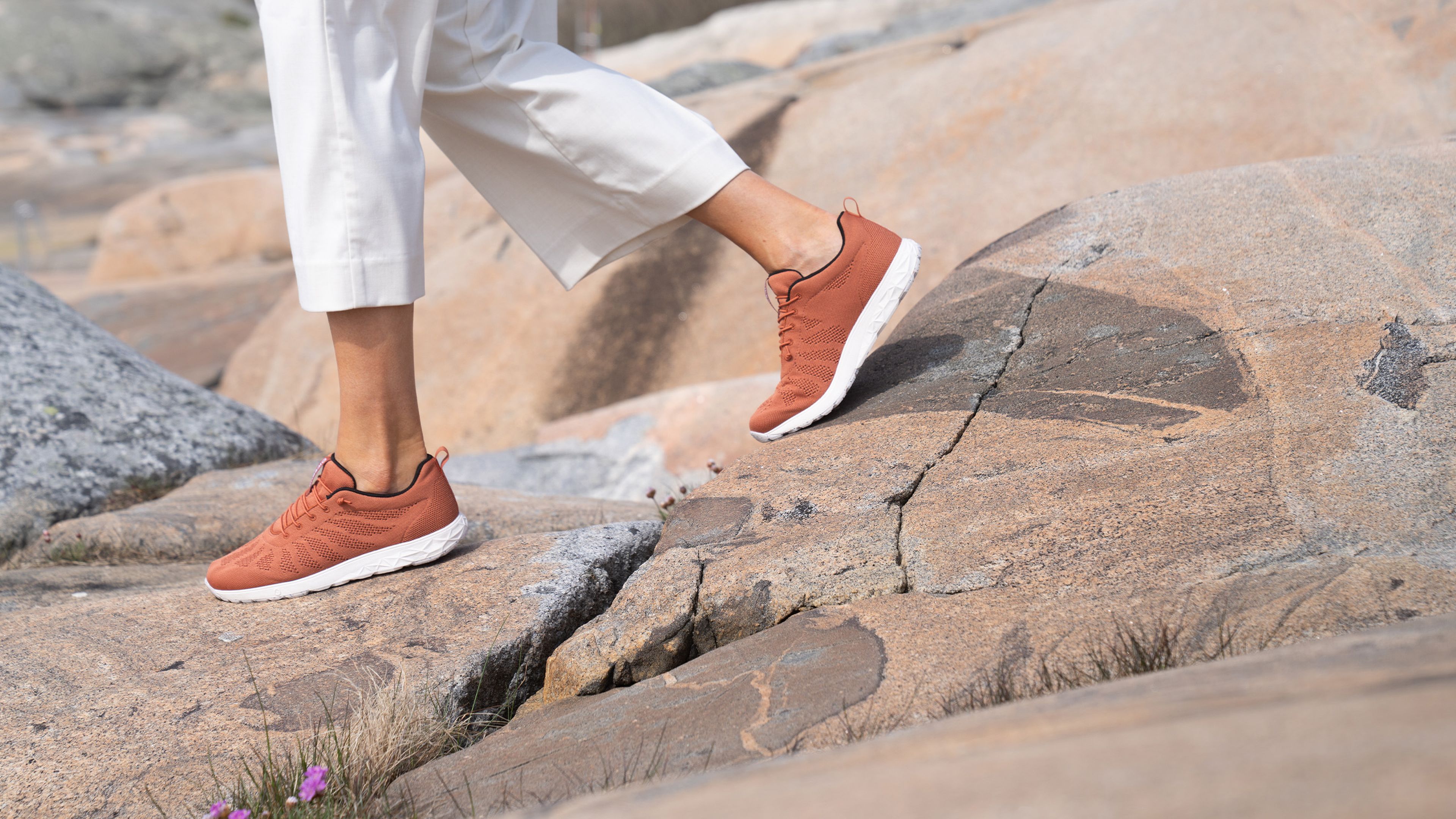Person wearing Icebug Eli RB9X sneakers and white pants walking on cliffs..