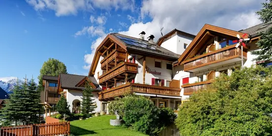 Hotel Montana in South Tyrol with white facade, wooden balconies, and PV panels on the roof.