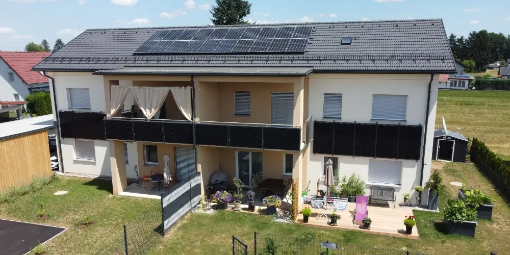 ChatGPT:  Four-unit house with rooftop PV panels; garden features flowers, seating areas, and raised beds.