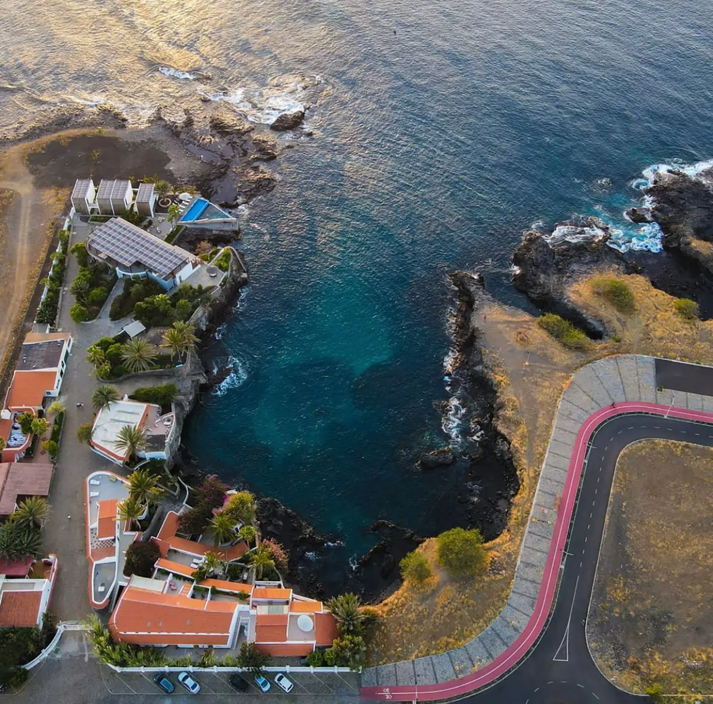 Bird’s-eye view of a hotel complex with a small cove of crystal-clear water
