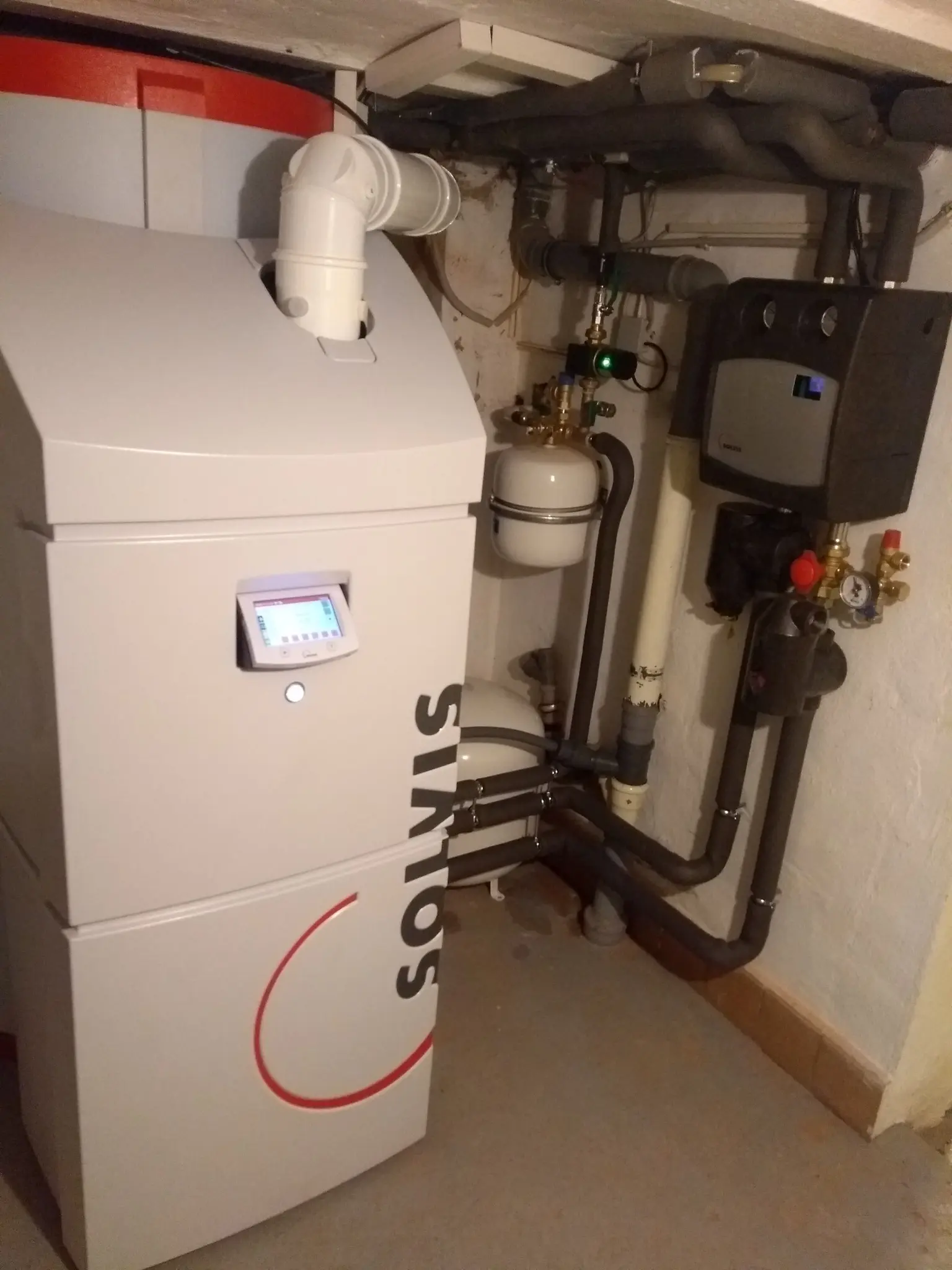 Modernized Solvis stratified storage tank with a digital display on the front and several pipes leading away from the heater.