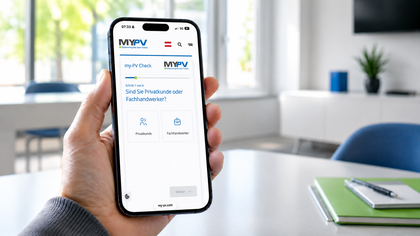 A person holding a smartphone displaying the MyPV website in German, with options for "Privatkunde" and "Fachhandwerker." Office setting in the background.