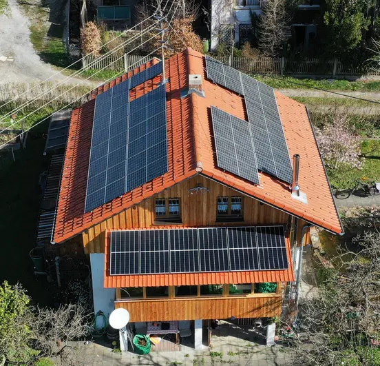 House with white and wooden facade, roof-mounted PV panels totaling 12.2 kWp.