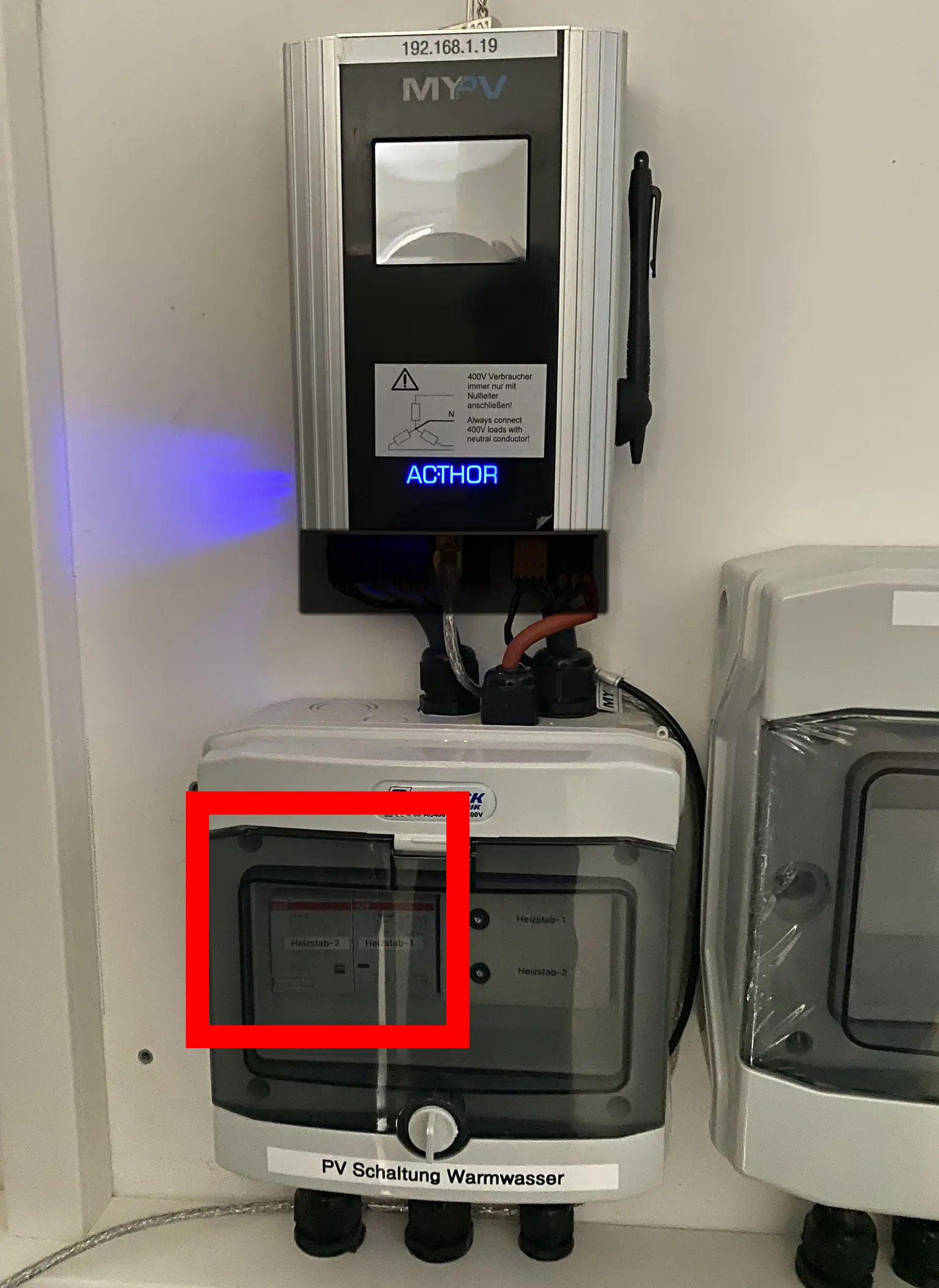 Electrical devices on a wall, including my-PV AC•THOR and PV hot water unit, with red rectangle highlighting display.
