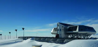 Princess Elisabeth research station in Antarctica with solar panels and wind turbines on snowy landscape under clear sky.