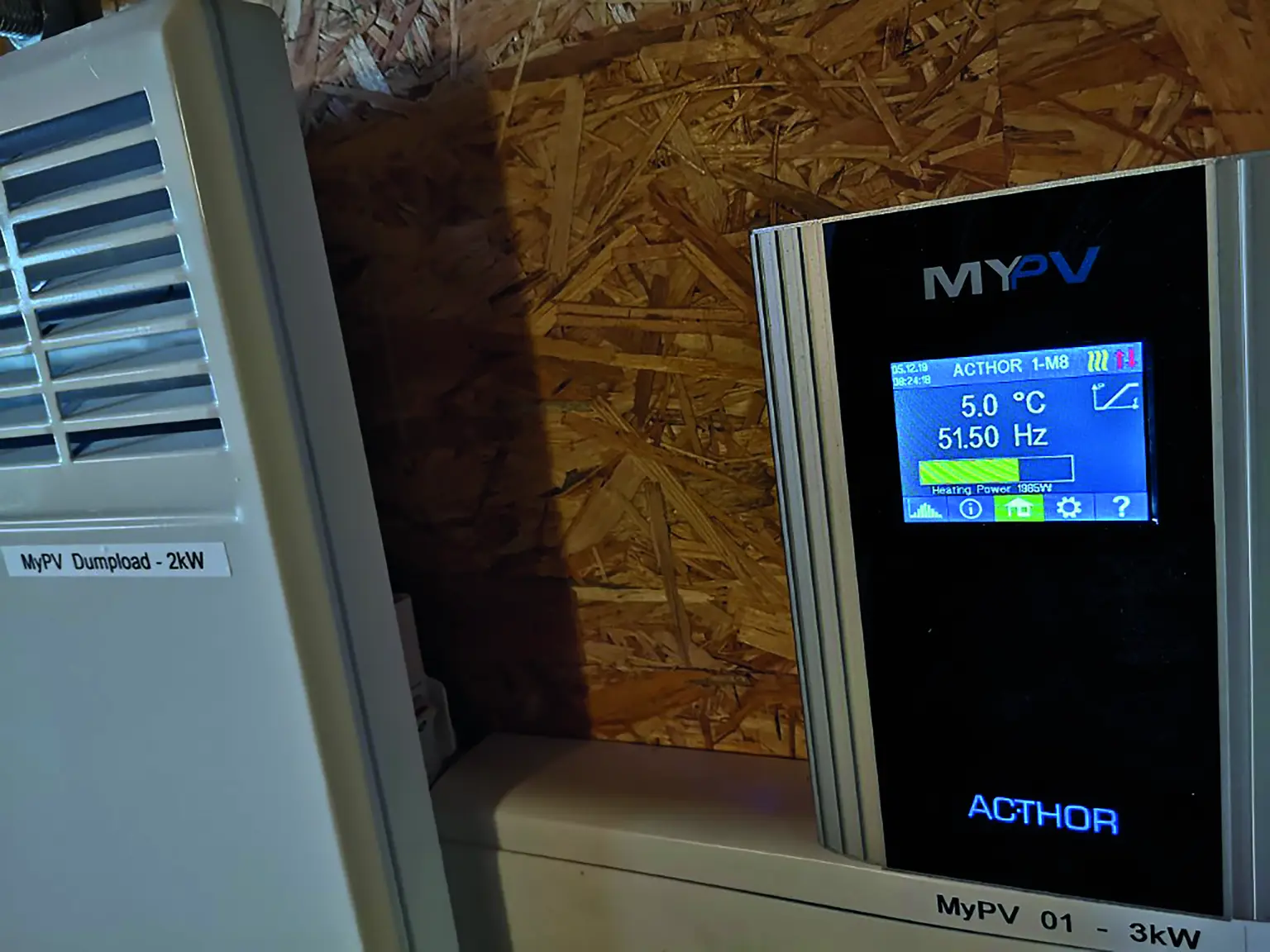 Close-up of my-PV AC•THOR showing 5.0°C and 51.50 Hz, mounted on wooden wall beside MyPV Dumpload unit.