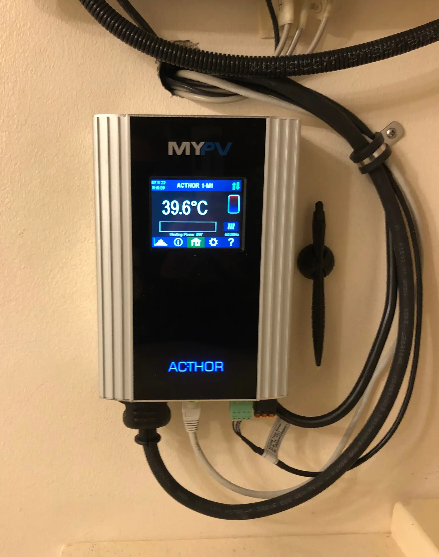 The AC•THOR is fully connected with visible cables, showing the home screen and a stylus mounted next to the device.