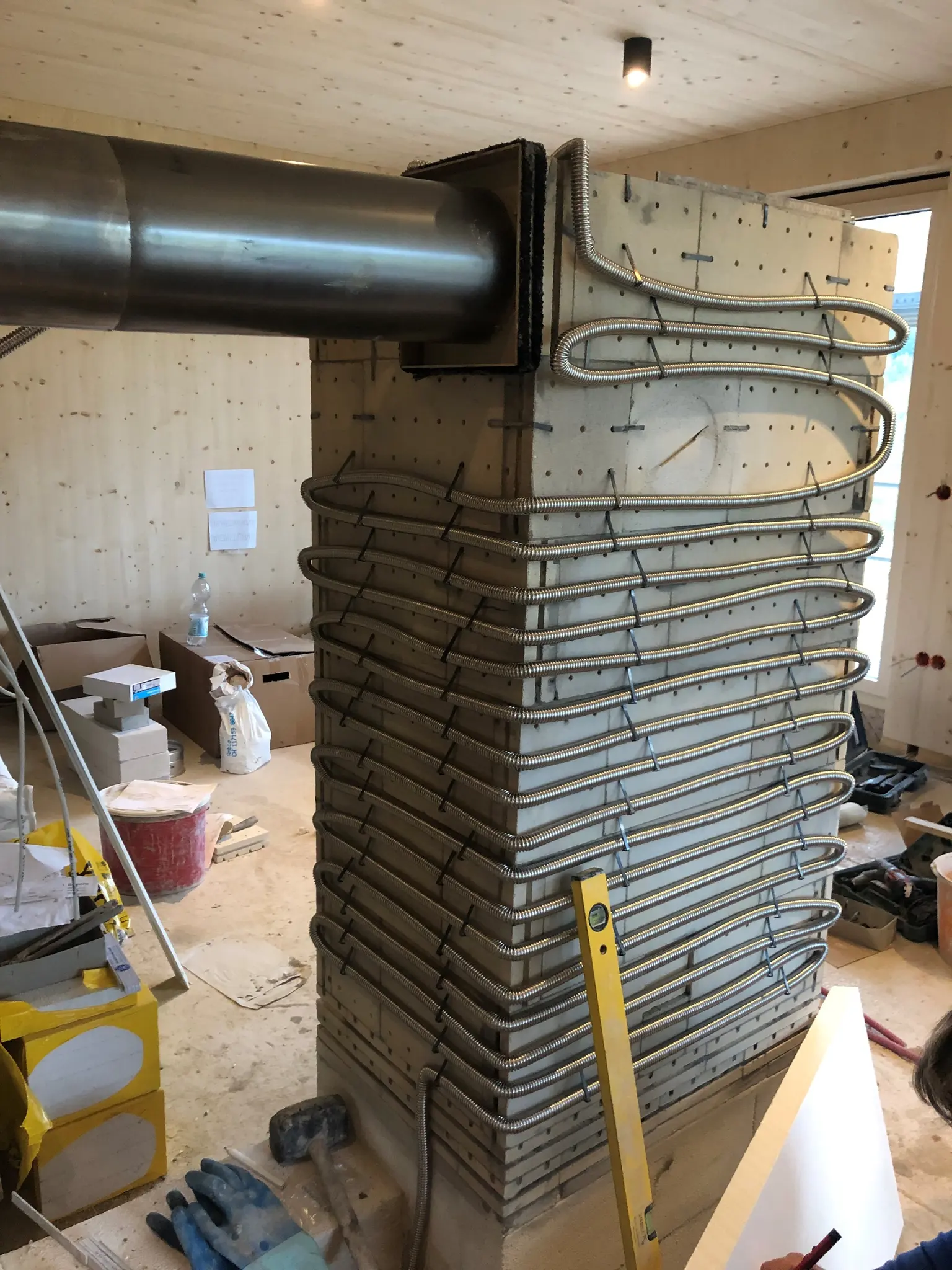 The stove, still under construction, is positioned in the center of the room, with the living area unfinished as well.