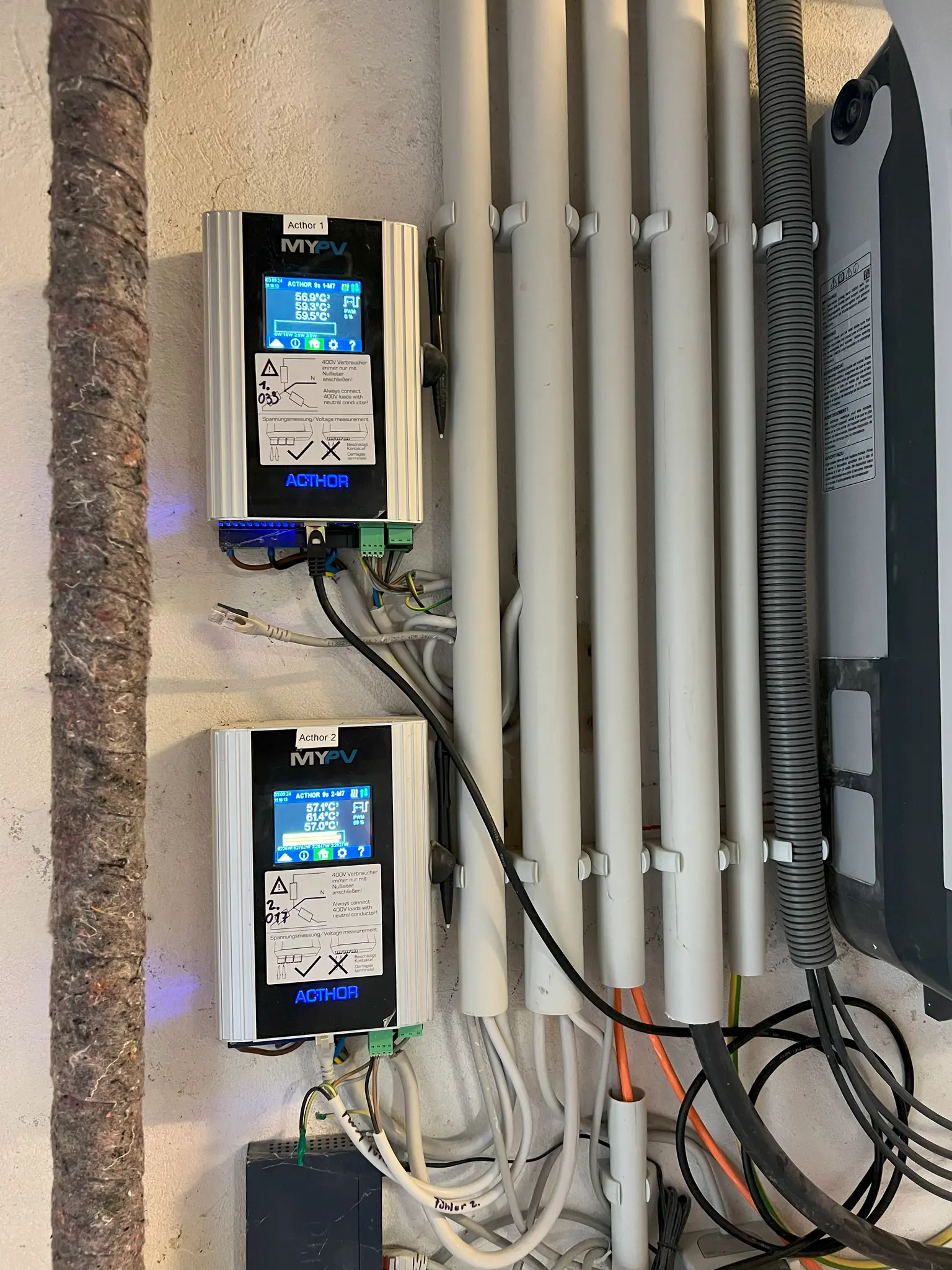 Two AC•THOR 9s from my-PV mounted on the wall and already connected, with several cable ducts next to them.