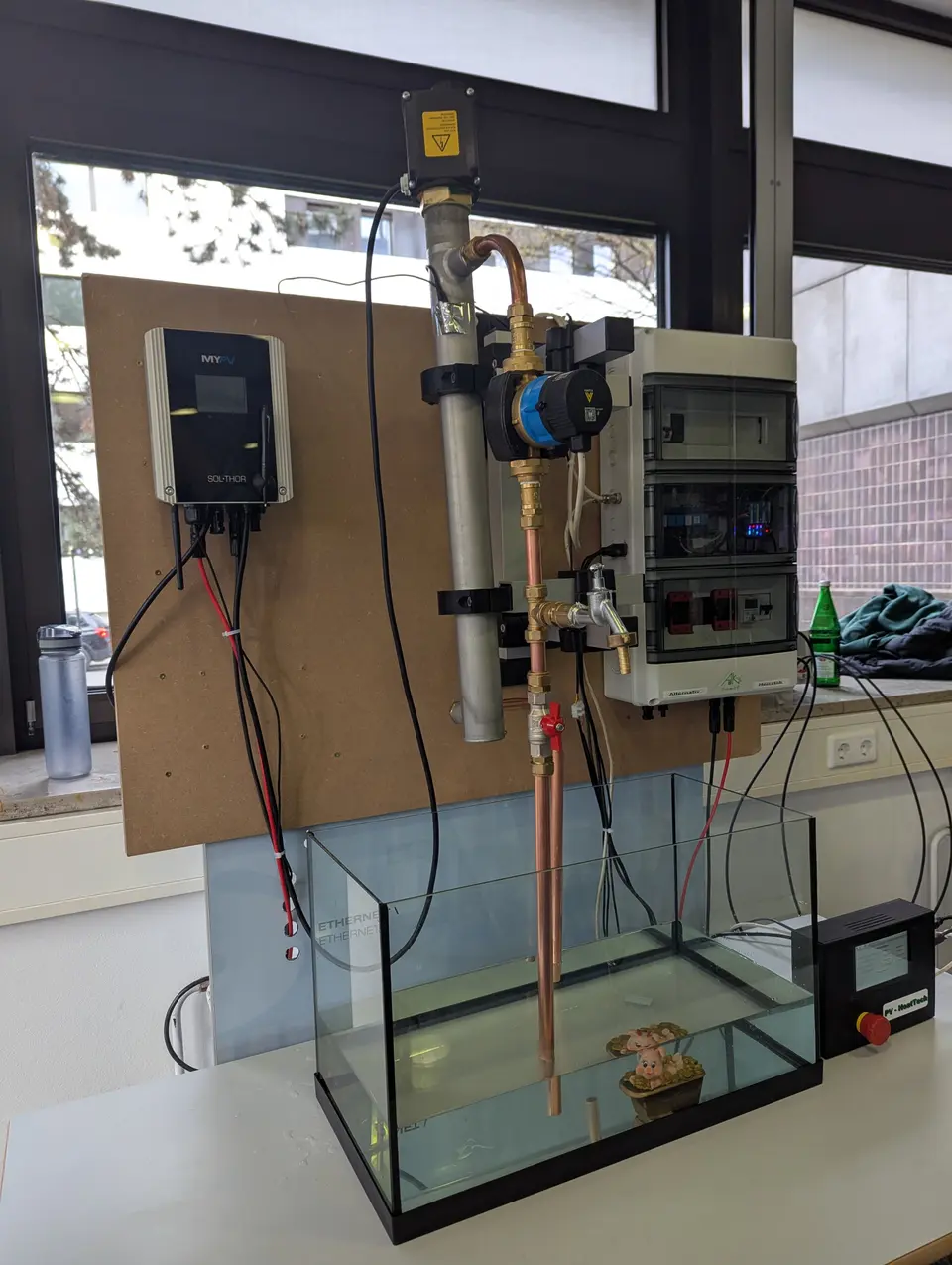 School project with AC•THOR, control cabinet, heating element, and small water tank demonstrating solar-electric technology.